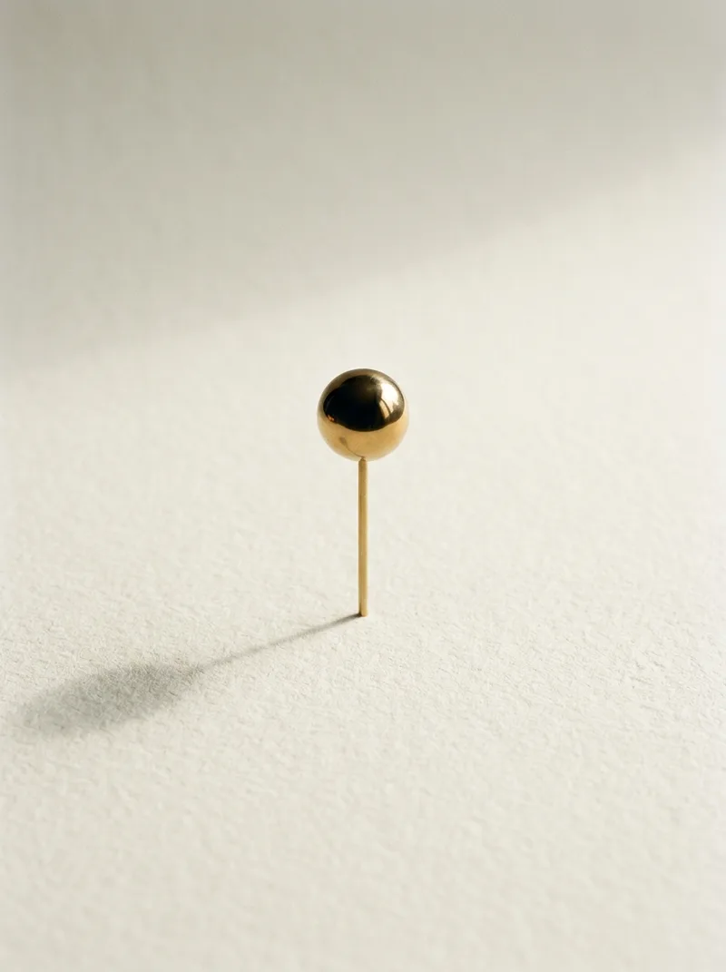 A single brass sphere standing alone on an empty sheet of paper