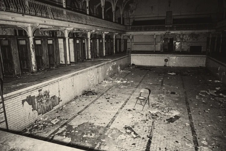 The empty main pool of a closed Victorian swimming baths, tiles peeling